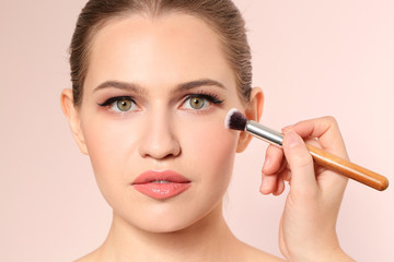 Fototapeta premium Professional visage artist applying makeup on woman's face on light background