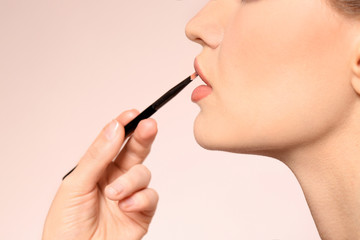 Professional visage artist applying makeup on woman's face on light background