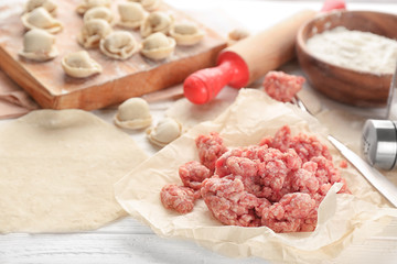 Minced meat and raw dumplings on table