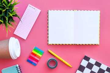 Student's desk. Notebook, stationery, coffee cup on pink background top view mock up