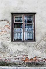 Old damaged wall with window in wooden frame.