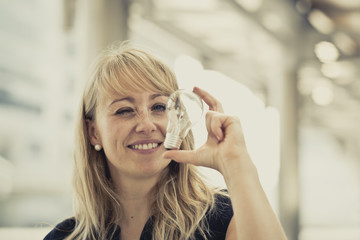 Portrait of young beautiful business woman holding bulb and present to the camera, with blurred background. Vintage color.