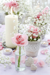 Floral arrangement with pink roses, gypsophila paniculata and candles.