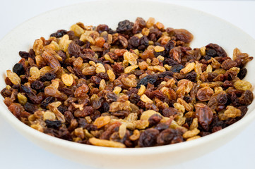 Yellow and brown raisins in a small white ceramic plate on the white table