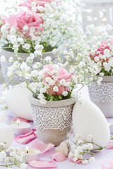 Floral arrangement with pink roses, gypsophila paniculata and candles.