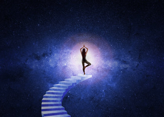 Woman in yoga position in front of the starry universe