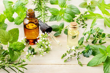 fresh herbs, leaves, flowers and essential oil on the wooden board - obrazy, fototapety, plakaty