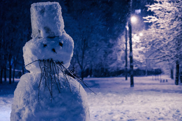 Angry, sad snowman forholiday of Halloween or Christmas, decorated with branches. Winter background.