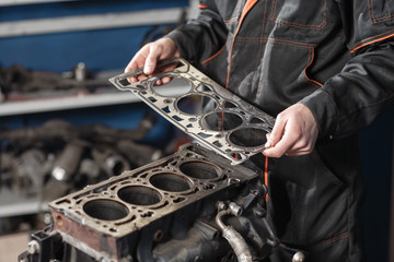 Sealing gasket in hand. The mechanic disassemble block engine vehicle. Engine on a repair stand...