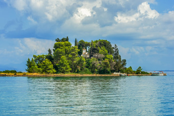Small green island with church on Ionian sea near Corfu island, Greece.