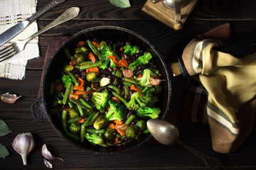 Vegetable stew in a frying pan on a dark wooden table