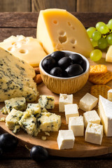 Various types of cheese on wooden cutting board.