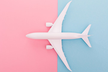 Miniature toy airplane on blue and rose background. Trip by airplane. Top view