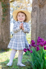 Toddler girl playing with tulips outside in spring