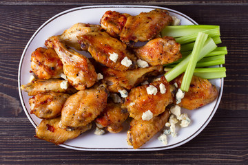 Buffalo chicken wings on white plate on wooden background