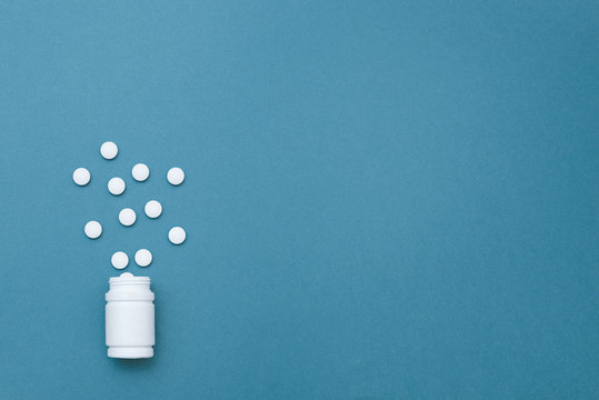 the photo of white tablets and drugs on a blue background