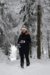 Pregnant woman a walk in winter landscape, beautiful snow-covered countryside. woman wearing black coat and winter hat.