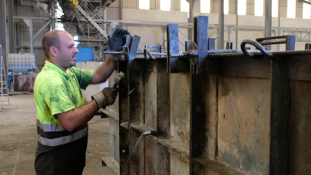 Man working in concrete factory adjusting structures