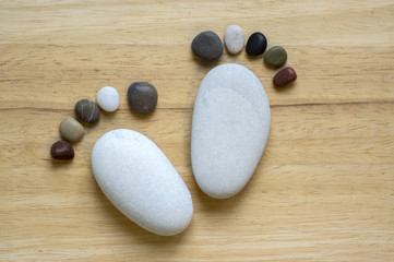 Fototapeta na wymiar Two tiny stone feet and ten toes on wooden background, stone in the shape of a human feet