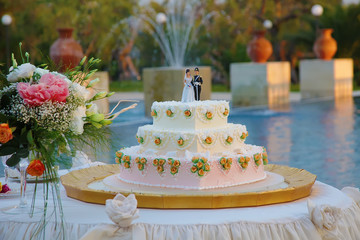 Wedding cake with the decoration of the bride and groom on top