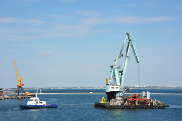Tugboat assisting floating cargo crane