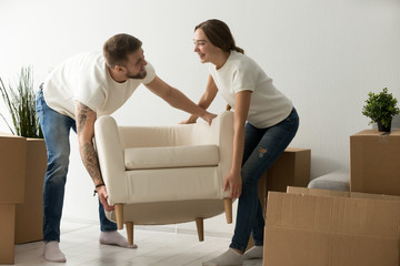 Young couple carrying chair together, house improvement, modern furniture in new home concept, man...