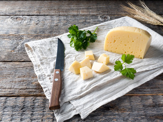 Piece of cheese with parsley on a linen towel Rustic wooden background