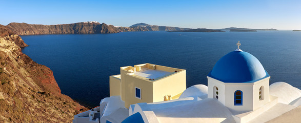 Obraz premium Panoramic image of local church with blue cupola in Oia on Santorini island