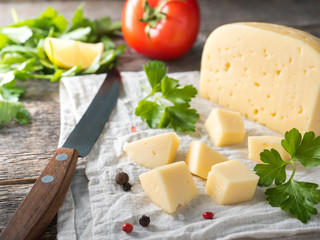 Piece of cheese with parsley, tomatoes on a linen towel Rustic wooden background