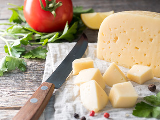 Piece of cheese with parsley, tomatoes on a linen towel Rustic wooden background