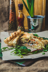 puff pastry stuffed with meat, carrots, potato pie, decorated with rucola, on a dark background...