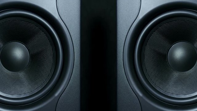 Close-up of two black round audio speakers vibrating from sound on low frequency. Modern sub-woofers.