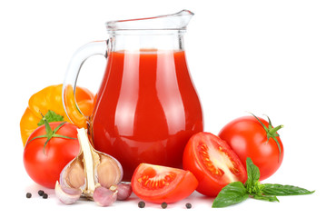 Tomato juice in glass jug with tomato, garlic, spices, and basil isolated on white background