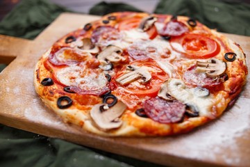Delicious freshly baked pizza on the wooden board, Italian food, restaurant concept