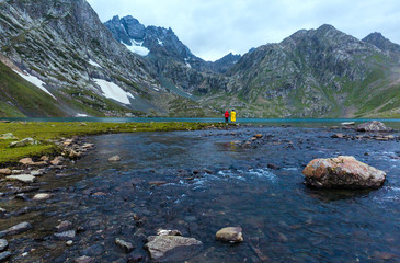 Friends fishing at Vishnusar lake on Kashmir great lakes trek in Sonamarg, India. Rocky terrain and  turquoise lake/tarn with snow mountains and glacier. Amazing nature. Hiking Trekking in Himalayas