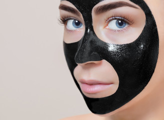 Facial black Mask  to the face of a beautiful woman. Spa treatments and care of the cats in the beauty salon.