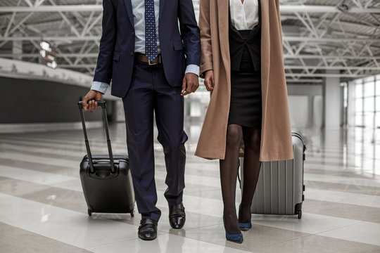 Close-up of legs of businessman and businesswoman are going to departure area with luggage. They are having business trip