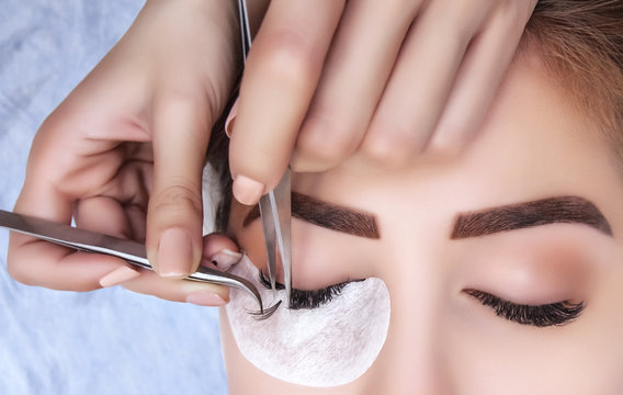 Eyelash extension procedure close up. Beautiful Woman with long lashes in a beauty salon.