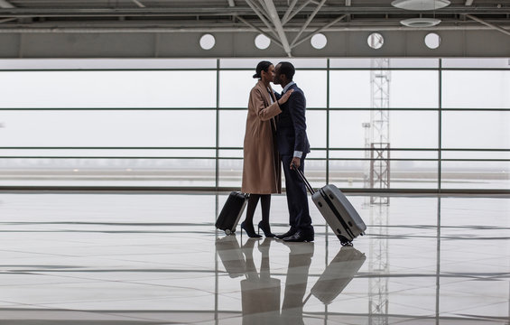 Pleasant meet. Full length of elegant woman and man are greeting each other at terminal lounge. They are standing with suitcases. Copy space in the left side