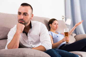 Man is sading when his wife is watching TV