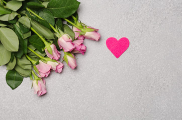 Pink roses and pink heart on grey background.