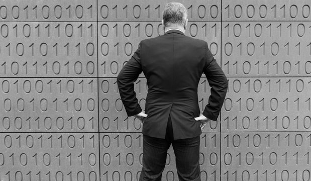 Ein Gesch&auml;ftsmann steht vor der Wand mit Bits und Bytes