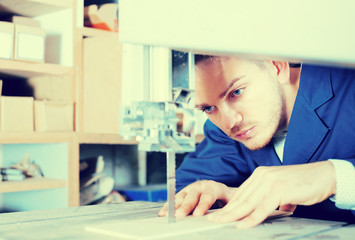 guy using ribbon saw to cut plank at workshop