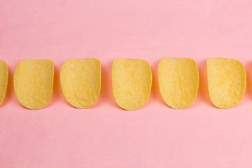 Potato chips on pastel pink background in minimalism style.