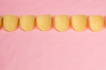 Potato chips on pastel pink background in minimalism style.