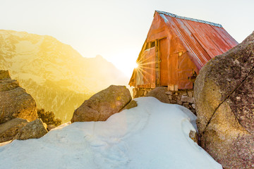 Secluded & beautiful Cabin in the snow mountains at Triund hill top, Mcleod ganj, Dharamsala, India during amazing sunrise from behind the snow mountains in winter. Sun burst, dawn break, golden hour