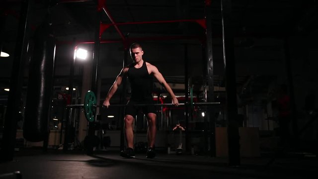 a man in black sportswear in the gym performs an exercise for a heavy detachment - a jerk.
