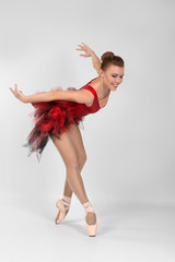 the ballerina in pointes and a red dress dances on a white background