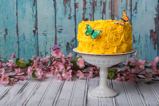 Yellow cake with turquoise and wood background and flowers  and butterflies