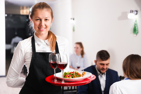 Portrait of woman waiter who is standing with dish in restaurante